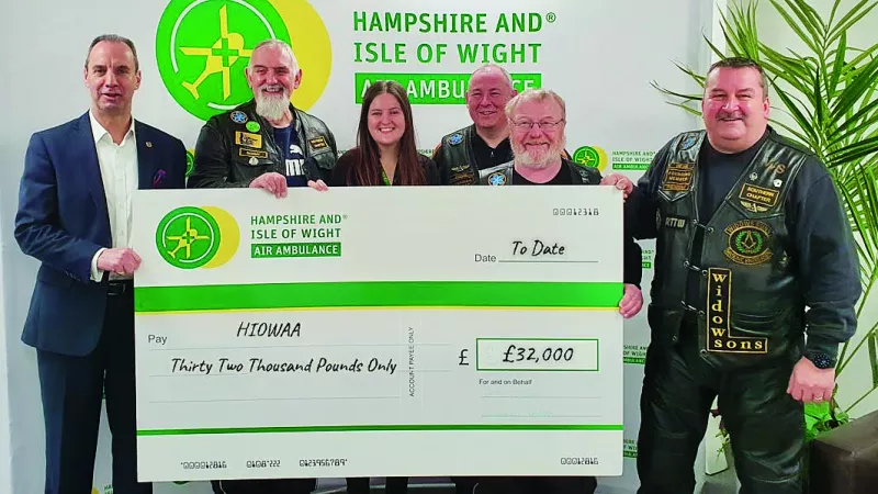 A group of people holding an oversized cheque and smiling to the camera