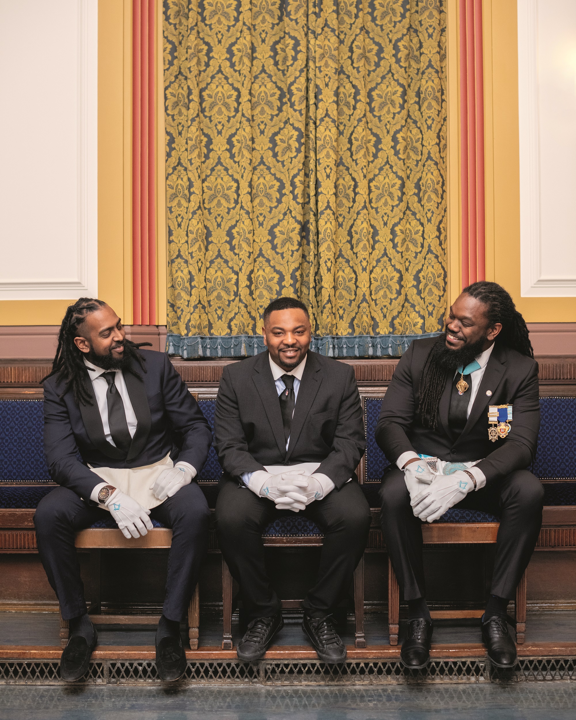 Young Freemasons in a Lodge room wearing suits and Masonic Aprons