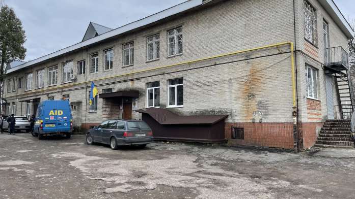 A two storey building with a ukrainian flag by the door.