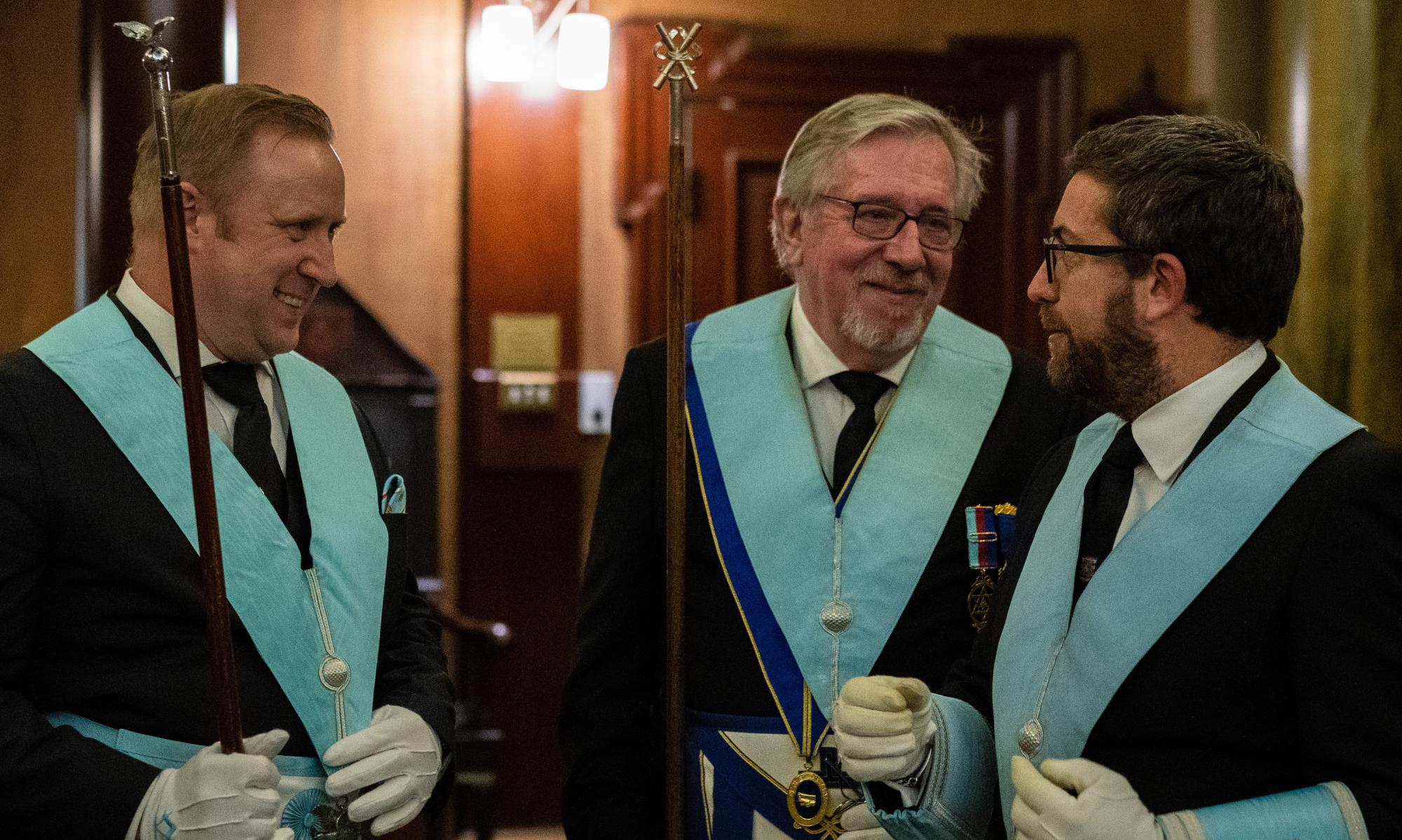 A trio of freemasons talking and laughing together.