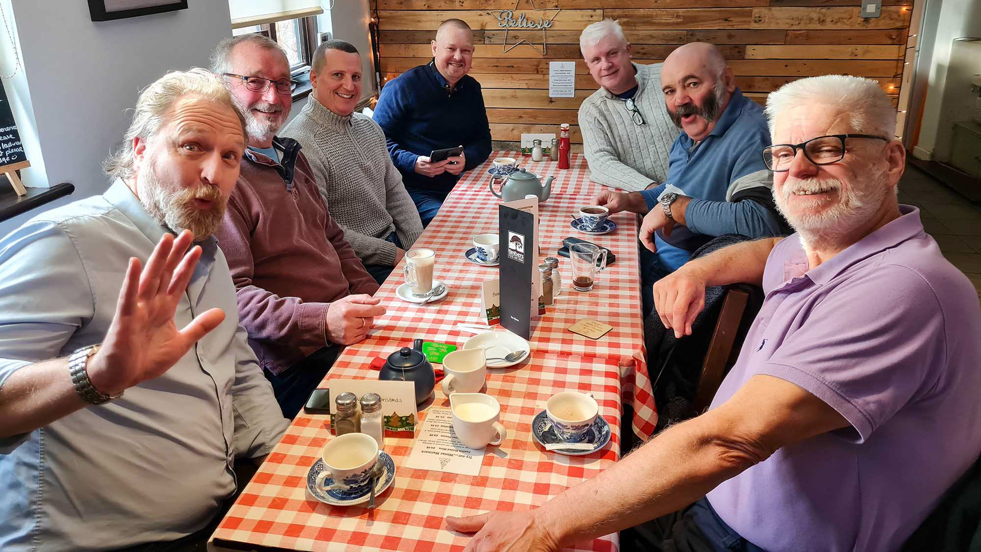 The members of Pyfleet Lodge Breakfast Club all sat around a long table with a red gingham tablecloth