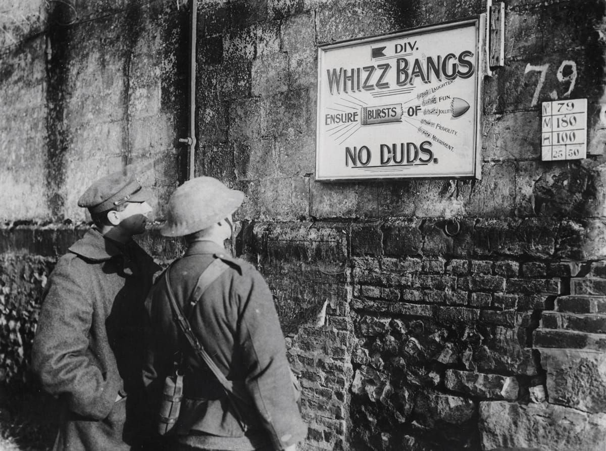 Two British soldiers read an advertisement by 5th Infantry Division for a Christmas Concert Party in Fonquevilliers, France, December 1916