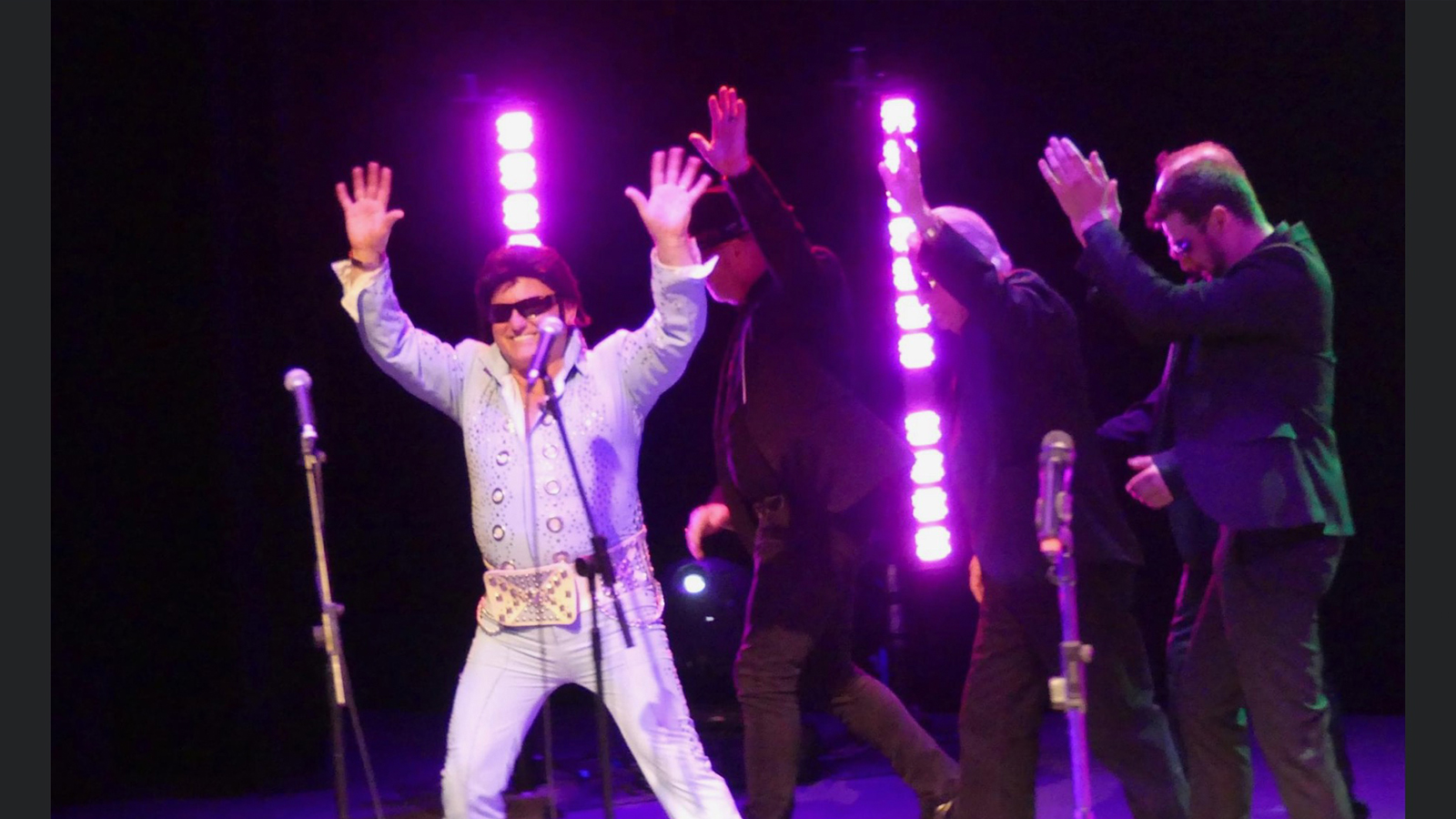Keith Davies dressed as Elvis Presley on stage with purple lighting