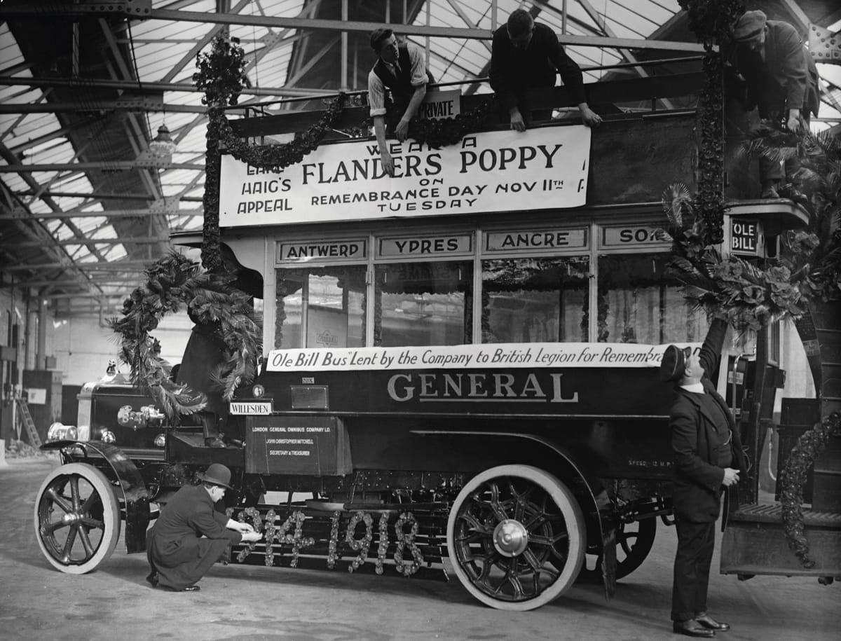 Workers decorate Old Bill, a WWI bus with garlands and wreaths for Poppy Day in honour of WWI Armistice. The symbol was adopted by Haig in 1921, as a founder of the Royal British Legion, c.1921