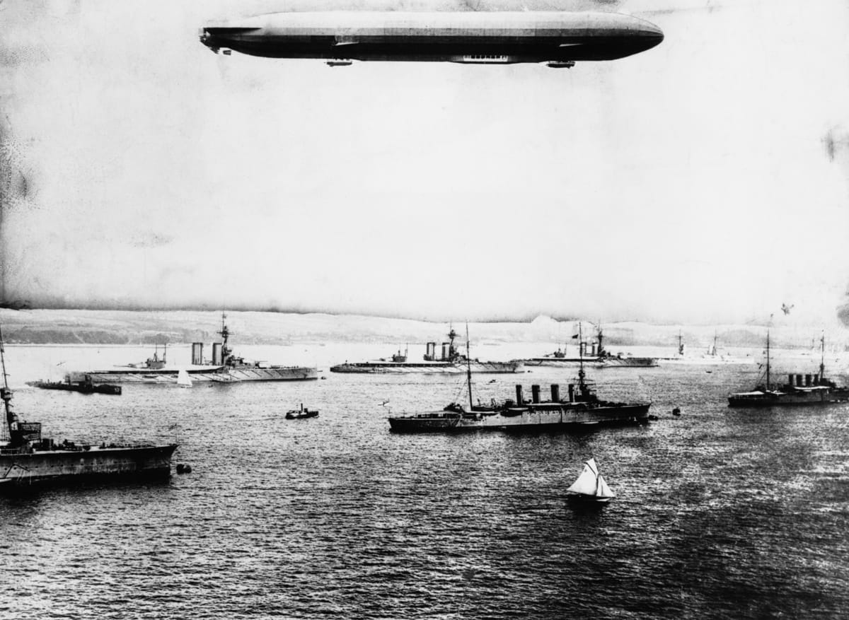 A British naval vessel visits Kiel Harbour, Germany on the eve of war with Zeppelin passenger Airship overhead, c.1914