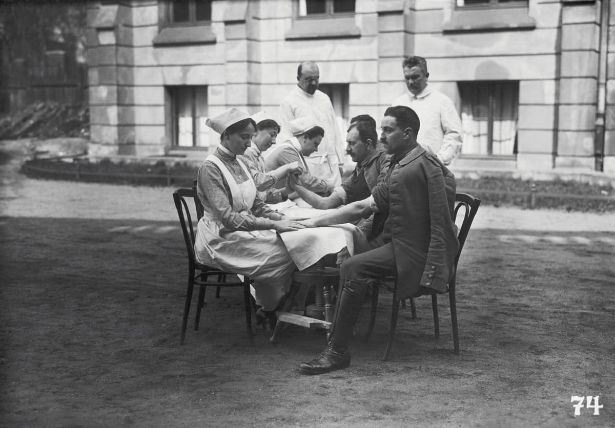 Wounded soldiers receive hand massages from nurses as part of recovery, c.1915