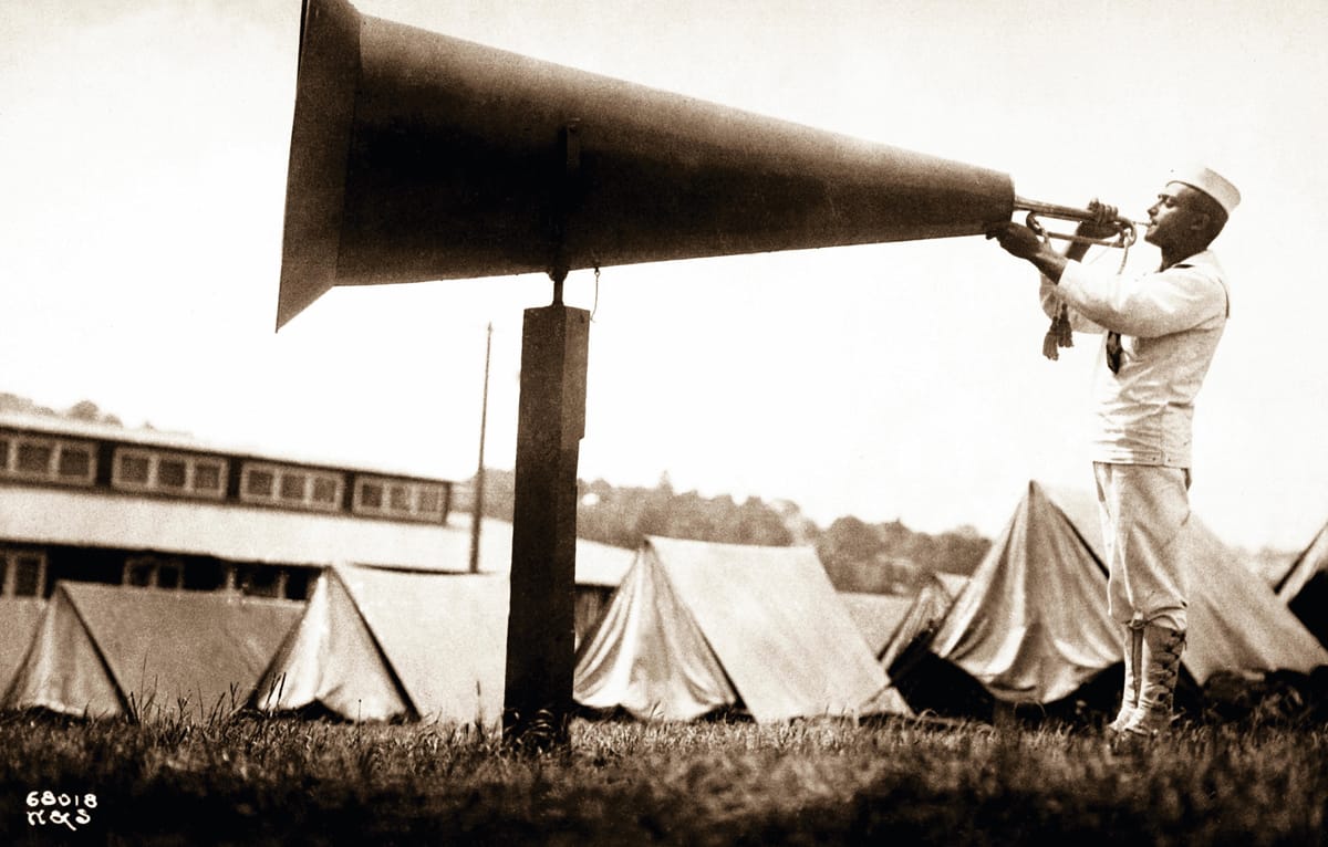 United States Naval Training Camp in Seattle, WA., a soldier amplifies the sound of his bugle by blowing into a giant megaphone c.1917