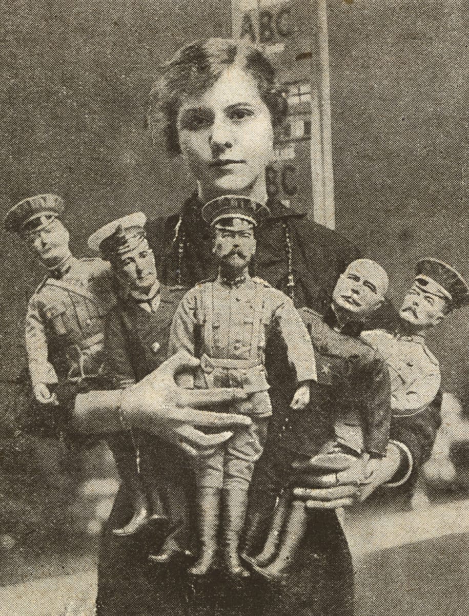 A worker poses with British made dolls representing The King, Lord Kitchener, Sir John French, Sir John Jellicoe, and General Joffre, c.1915