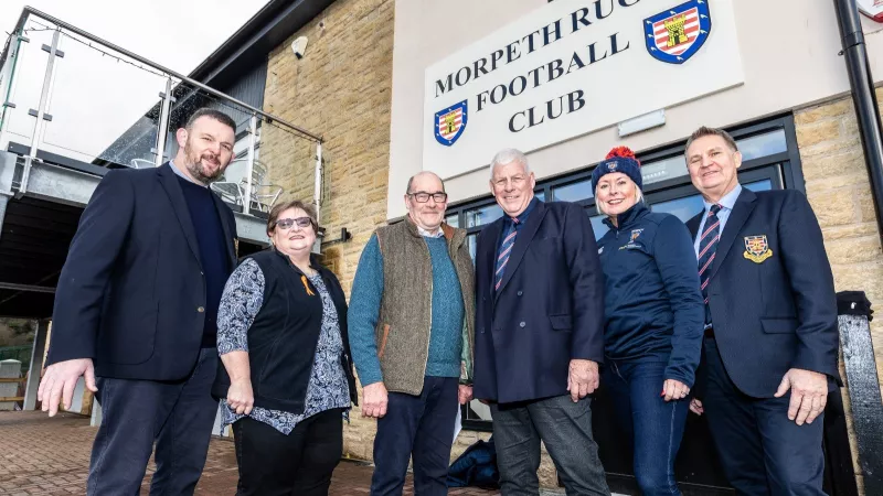A group of people stood in front of the Rugby Club doors.