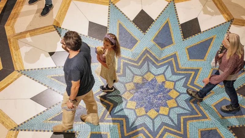 Visitors to Freemasons' Hall. The photo is of a man, a wom and a young girl, taken from above as they walk across art deco marble flooring.