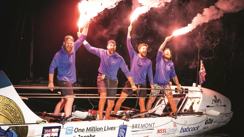 Photo of four men in a boat with fireworks in hand 