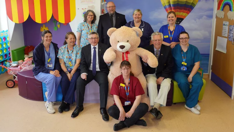 jpg ‘Charlie the Bear’ taking centre stage in the Caroline Thorpe Children's ward, on his left W Bro Charlie Yelland (Asst Provincial Grand Master, Devonshire Freemasons) on his right W Bro Keith Bower (TLC Devonshire), behind W Bro Adam Jeffery (Keeper of Bears in North Devon). Seated in front on floor, Pat Davies ( Adv Clinical Physiologist and NHS Bear administrator).
