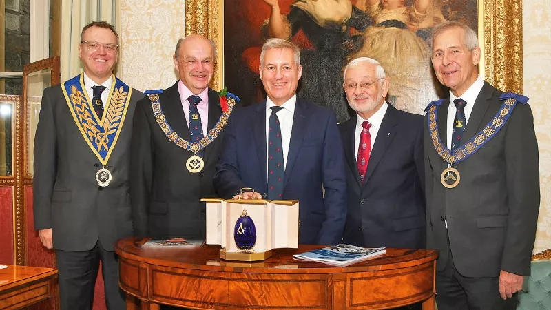 Freemasons stand around the blue Faberge Egg smiling