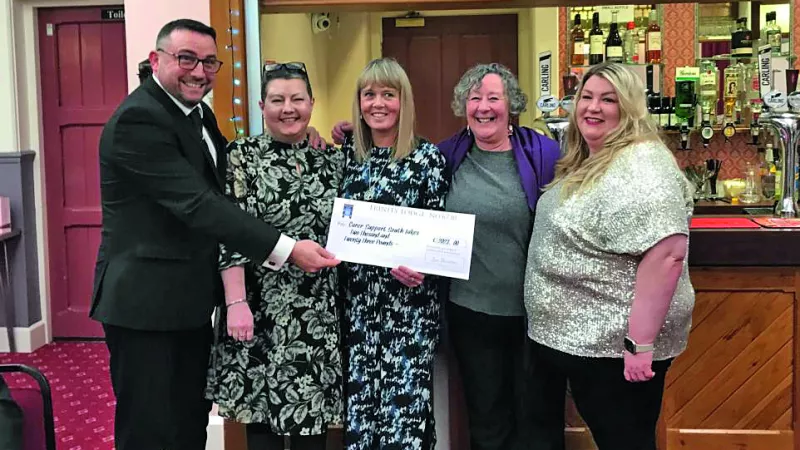 A group of people holding a giant cheque and smiling to the camera