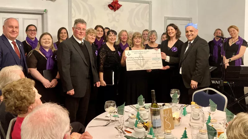 A group of people holding an oversized cheque and smiling to the camera
