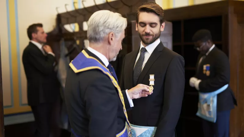 Two Freemasons wearing regalia and getting ready for a Lodge meeting