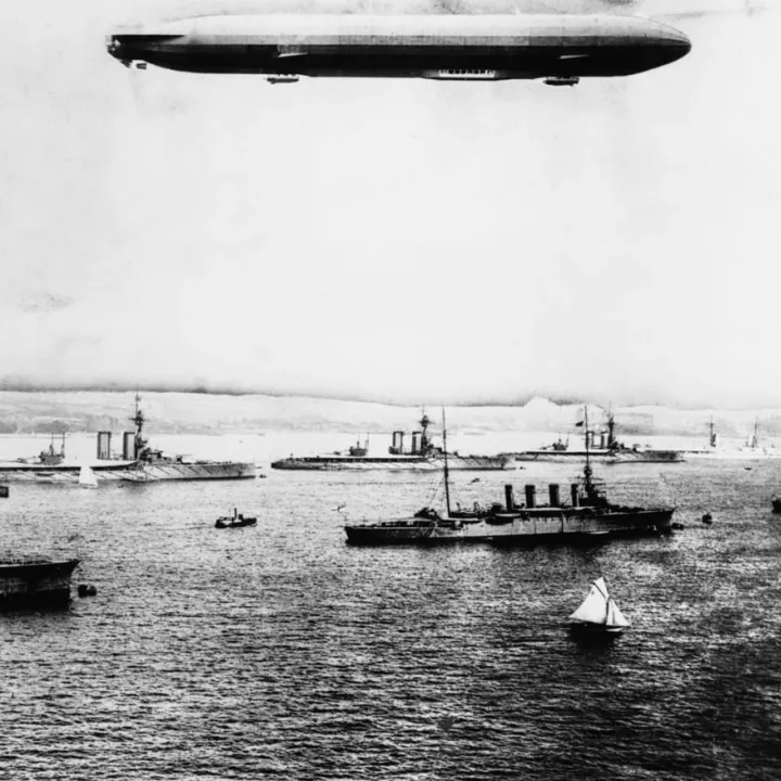 A British naval vessel visits Kiel Harbour, Germany on the eve of war with Zeppelin passenger Airship overhead, c.1914