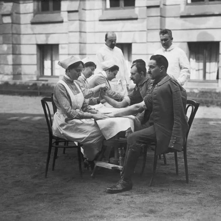Wounded soldiers receive hand massages from nurses as part of recovery, c.1915