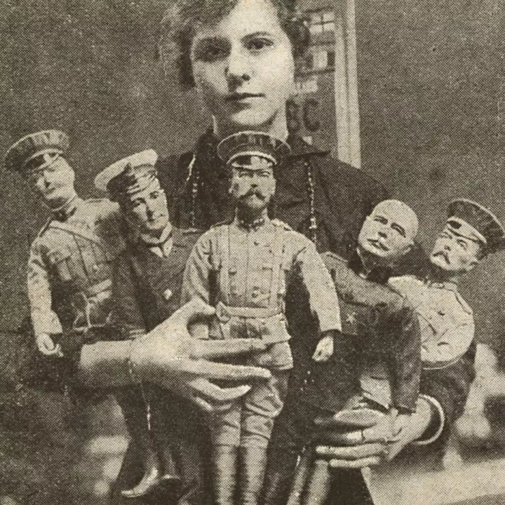 A worker poses with British made dolls representing The King, Lord Kitchener, Sir John French, Sir John Jellicoe, and General Joffre, c.1915